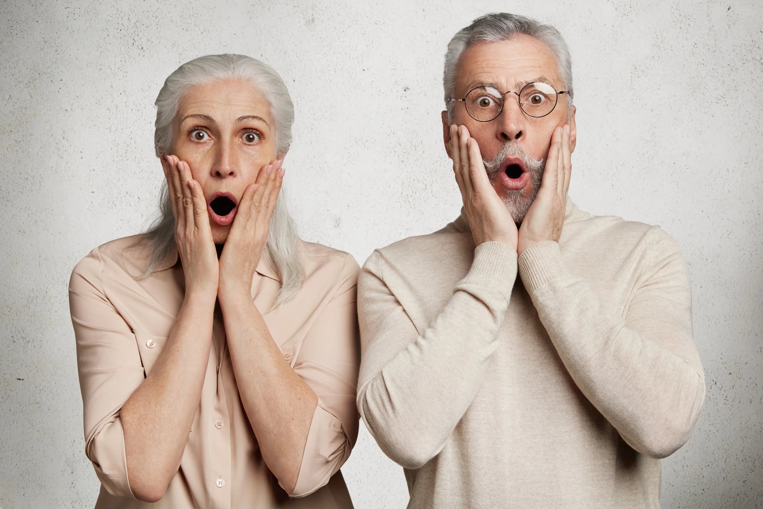 Surprised older couple with hands on their cheeks